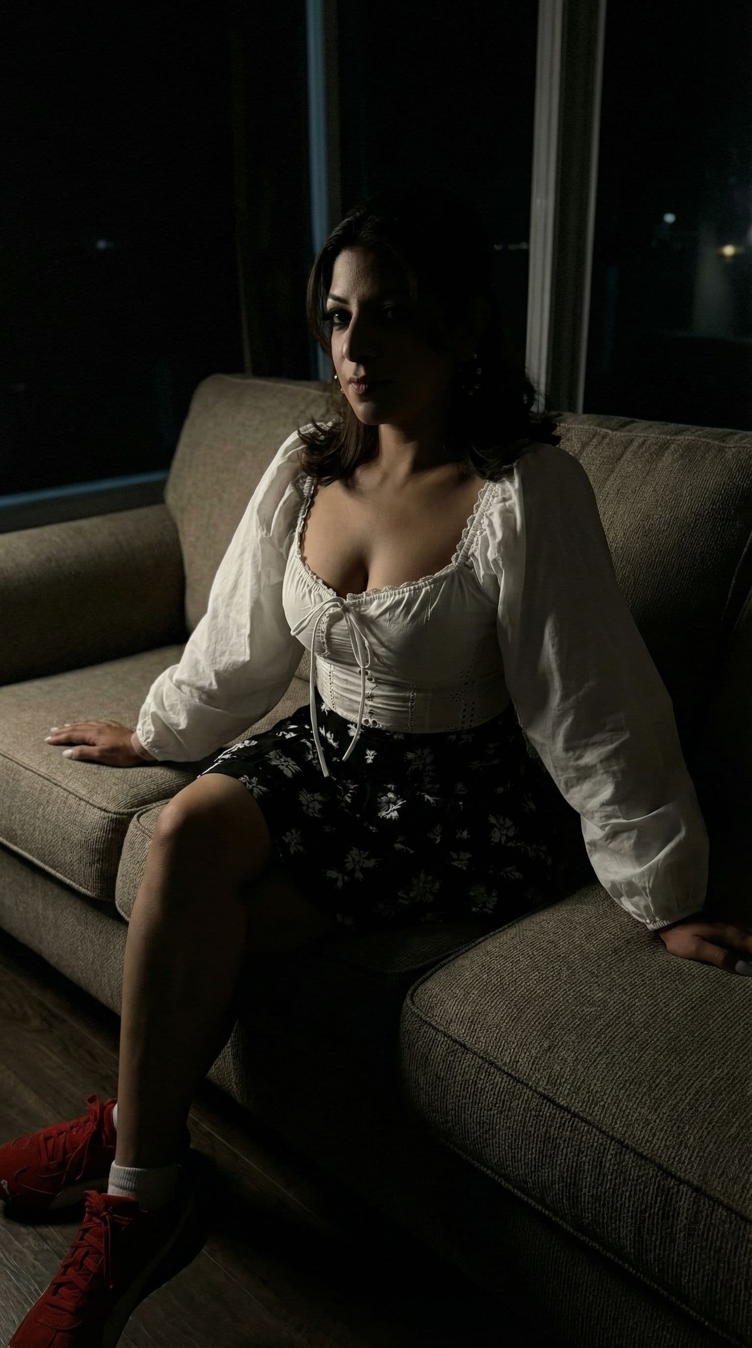 AI generated: Wearing same clothes, sitting on a couch, close view, 35-year-old indian woman, busty body, at night...