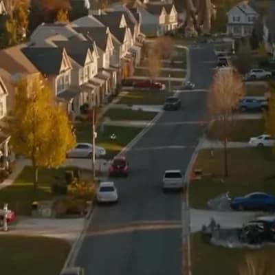 AI generated video: A massive T-Rex thunders through a quiet American suburban neighborhood, crushing cars and tearing u...